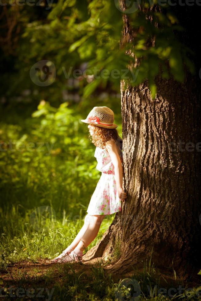 Girl stands near a tree in sunlight photo
