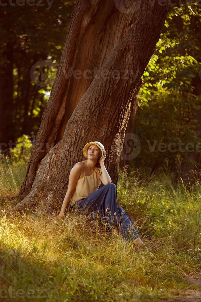 Romantic young woman sitting under a tree photo