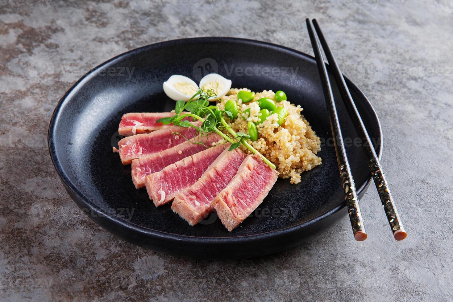 Black plate with quinoa and fried tuna slices photo