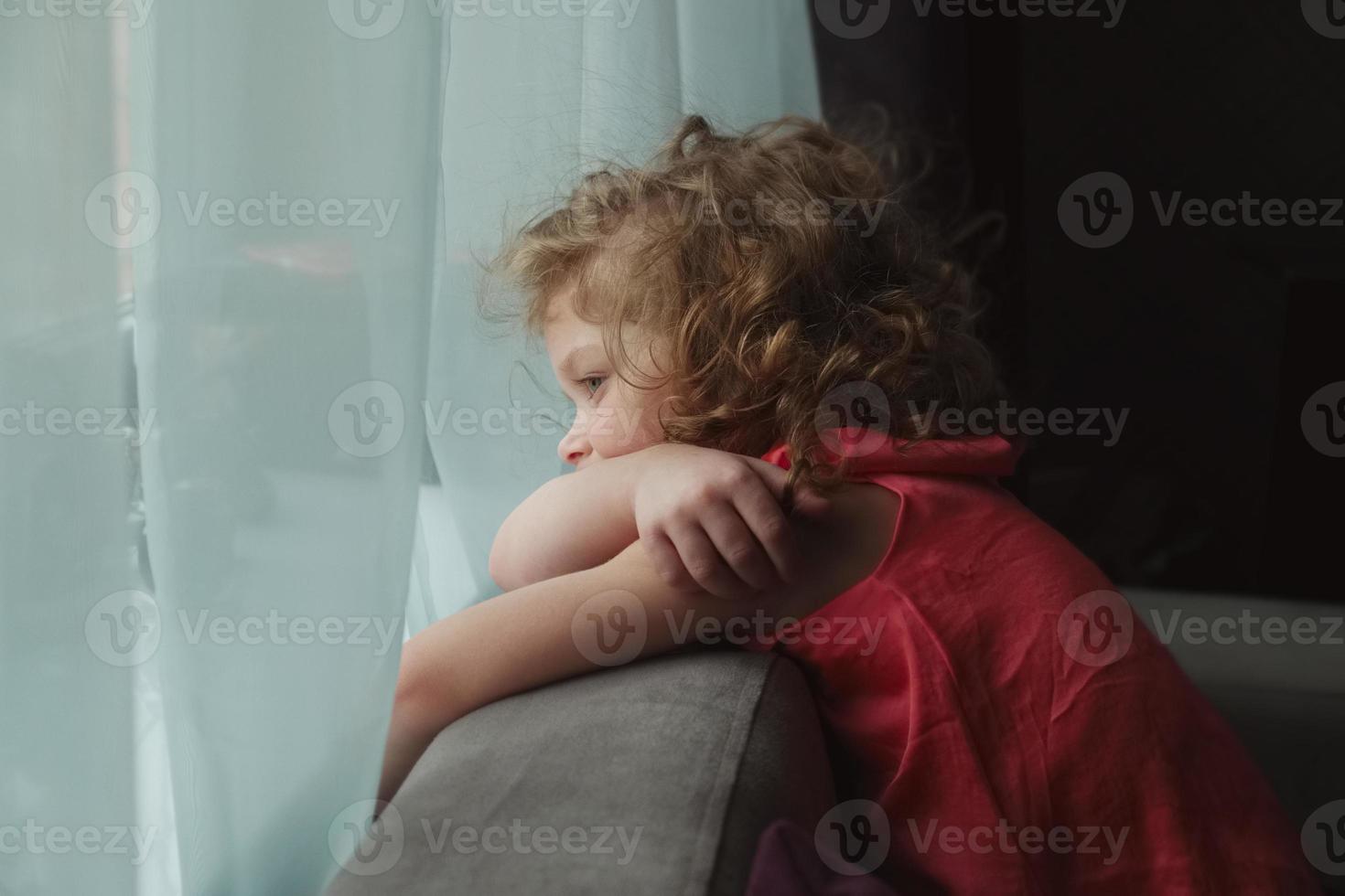 niña esperando a alguien y mirando por la ventana foto