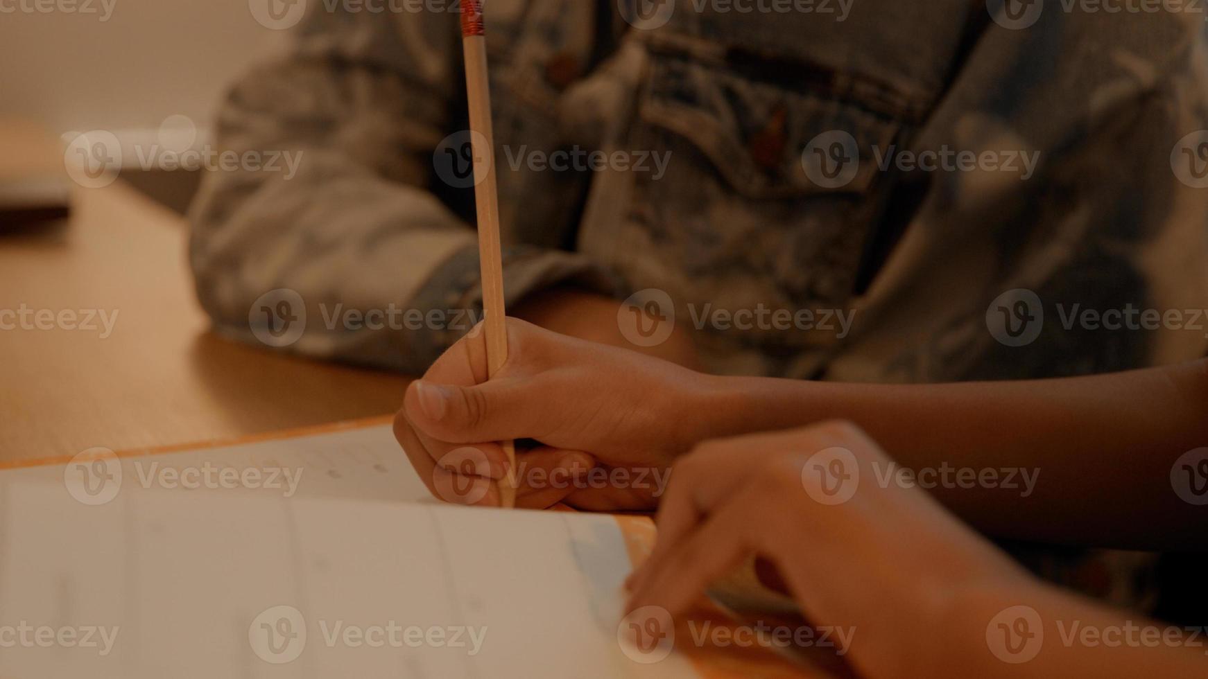 Woman helping girl doing homework at table photo