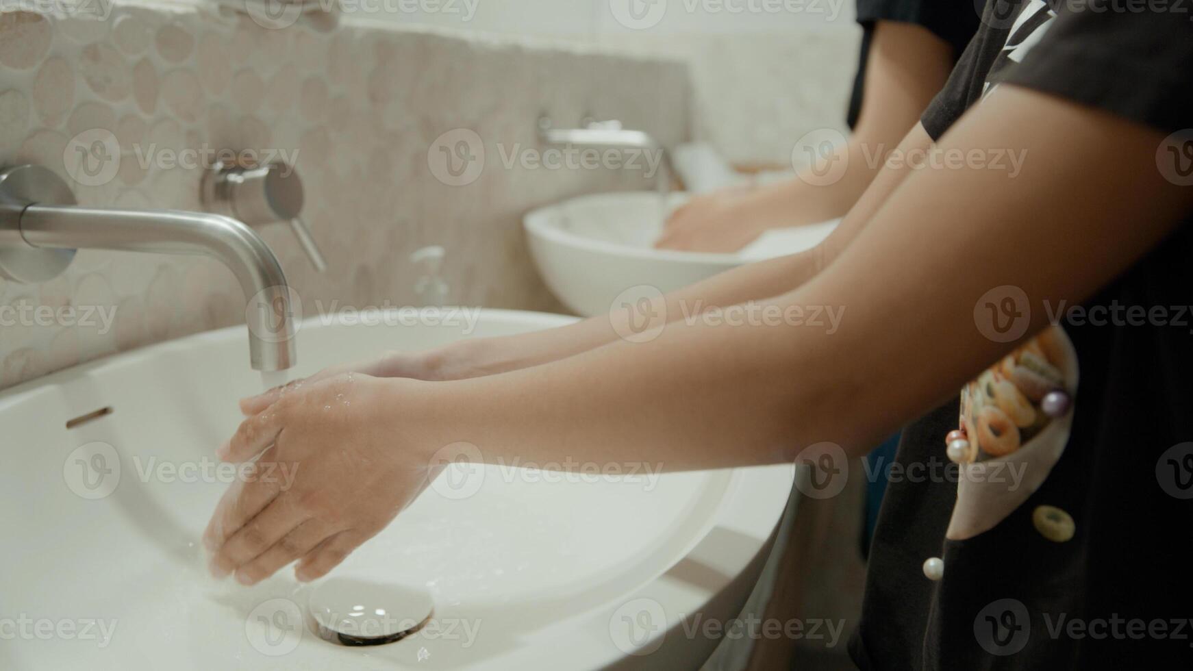 Woman and girl washing hands in bathroom photo