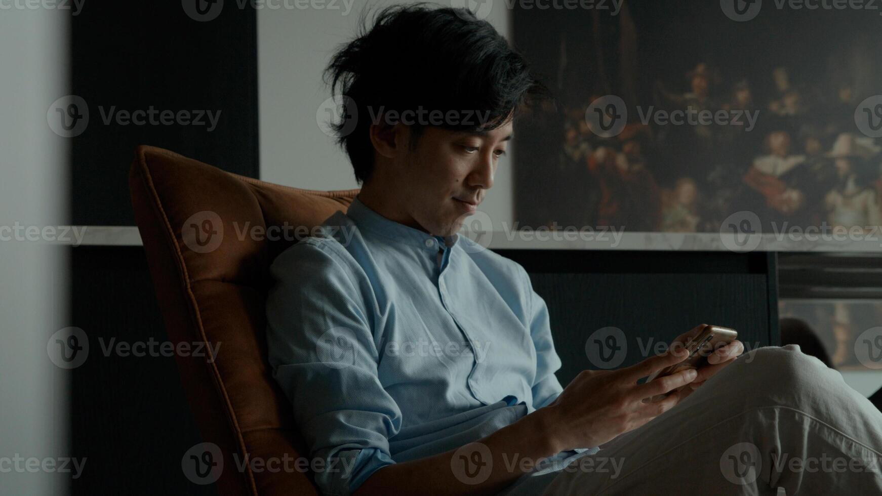 Man sits whilst typing on mobile phone and stares photo