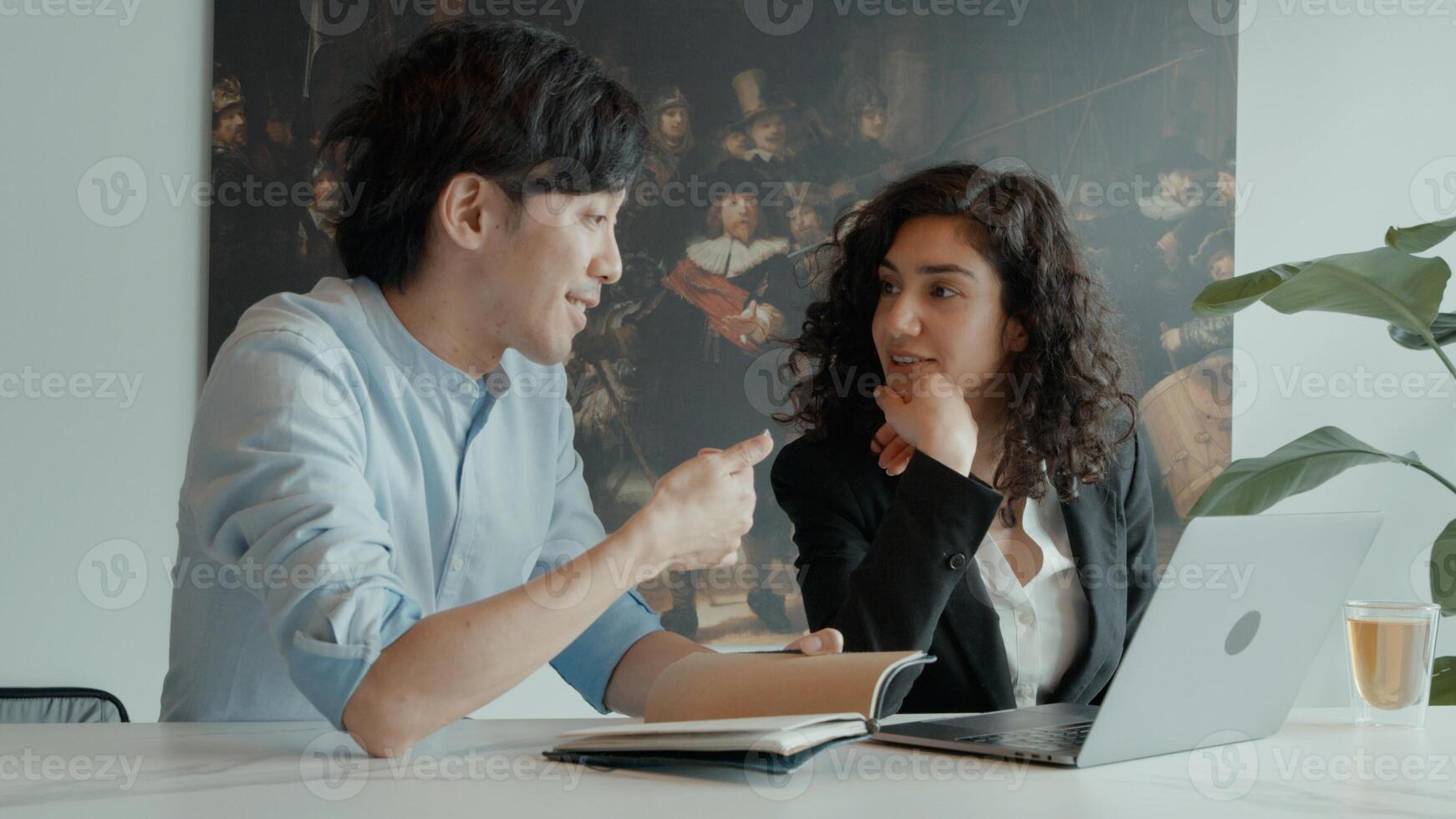 Woman and man at table with laptop having conversation photo