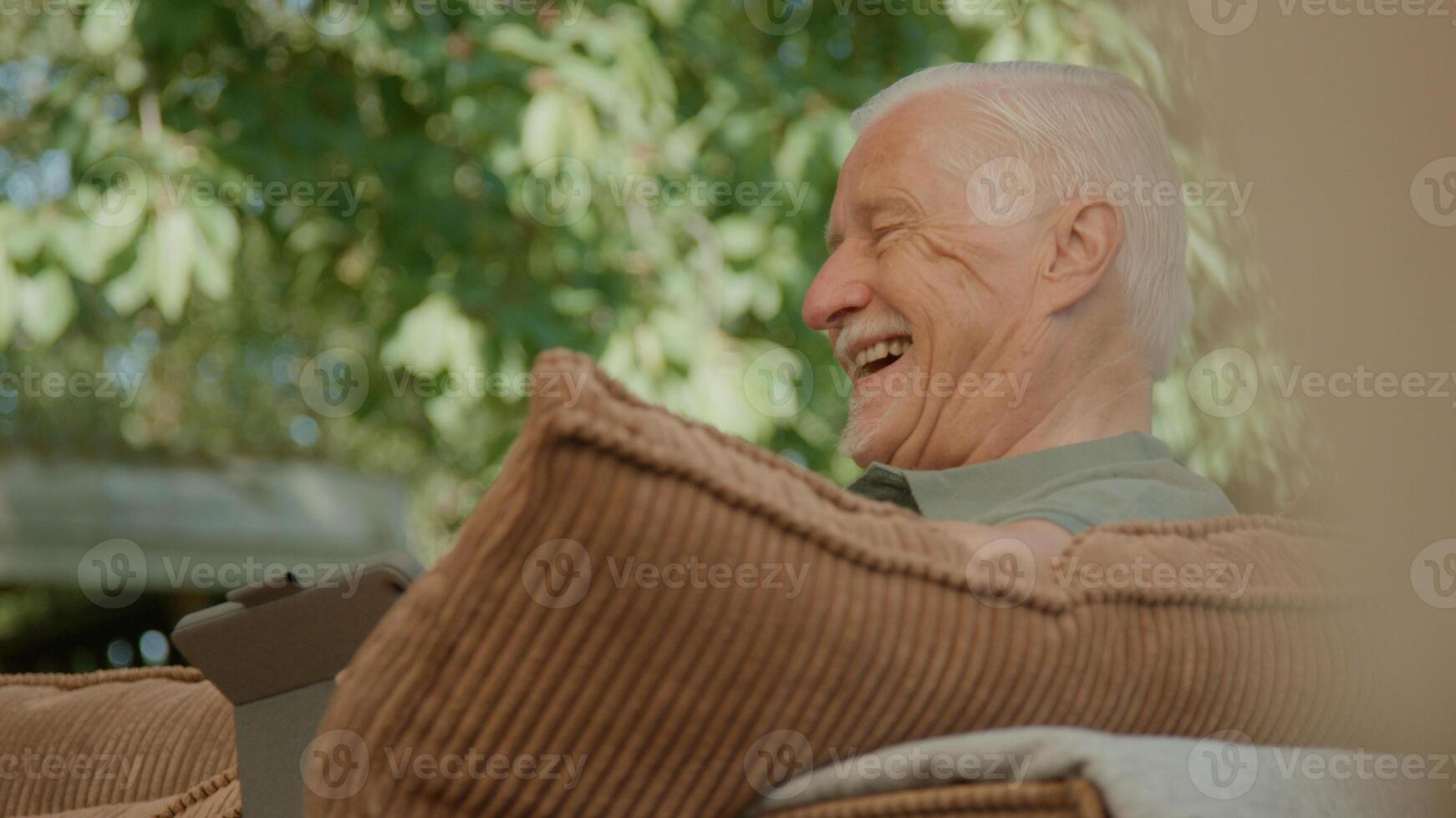 Man sitting in garden using tablet whilst talking photo