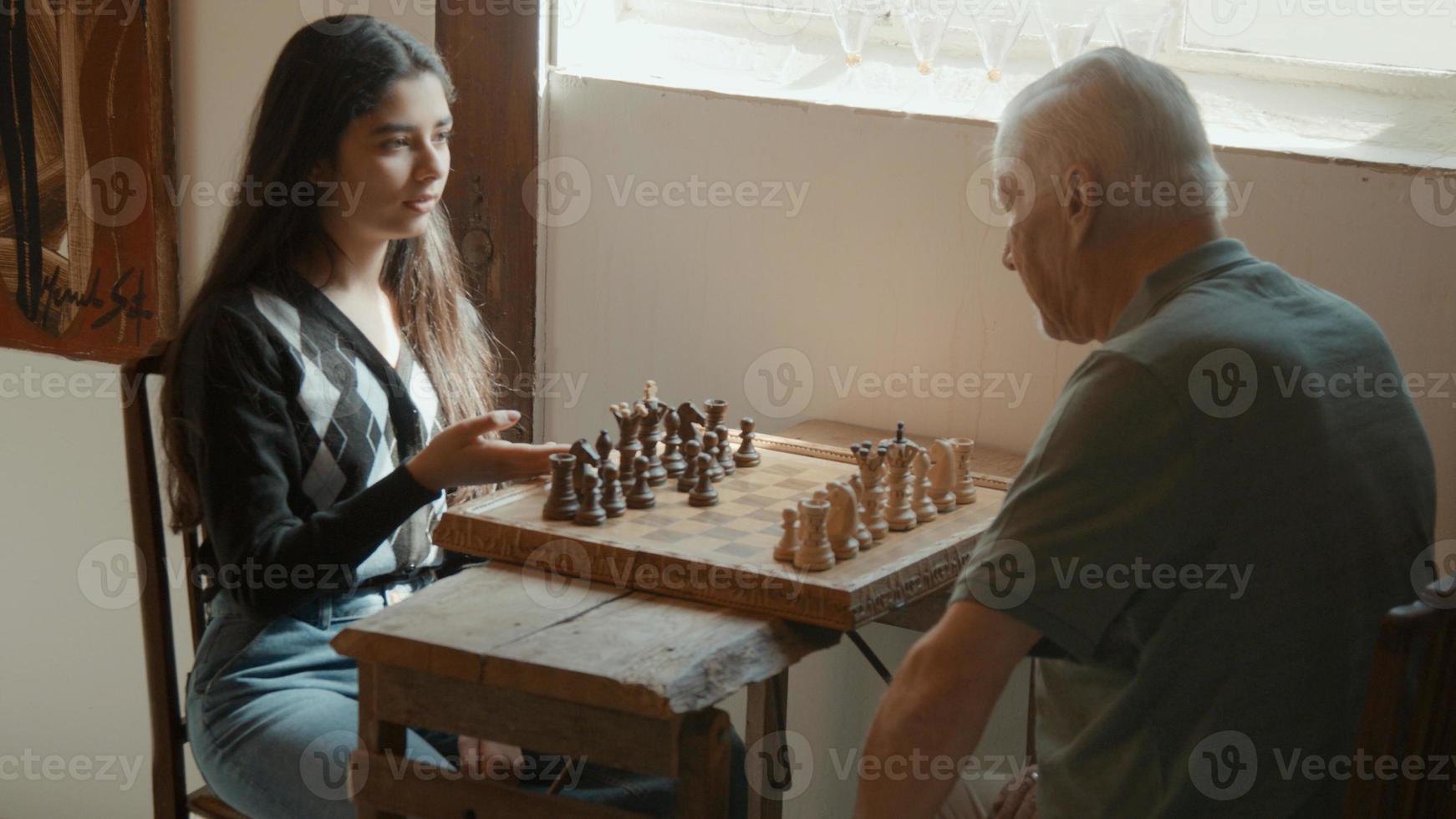 Girl explains how to play chess to man sitting at table photo