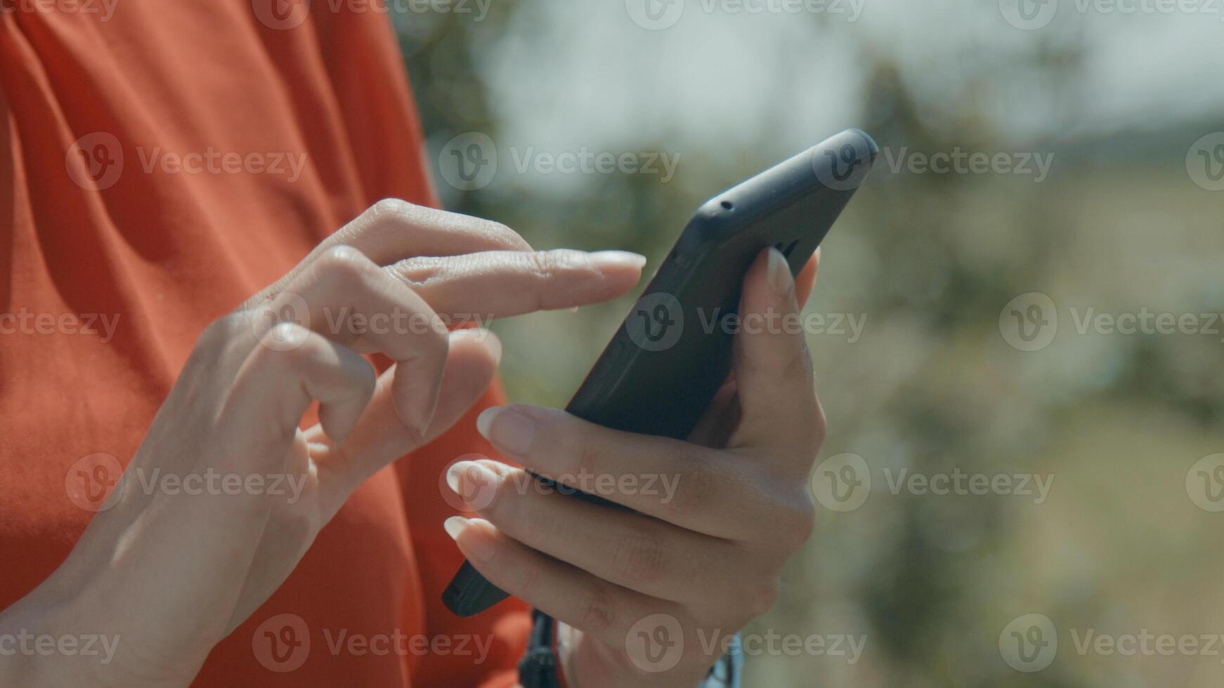 Hands of woman in green area typing on smartphone photo