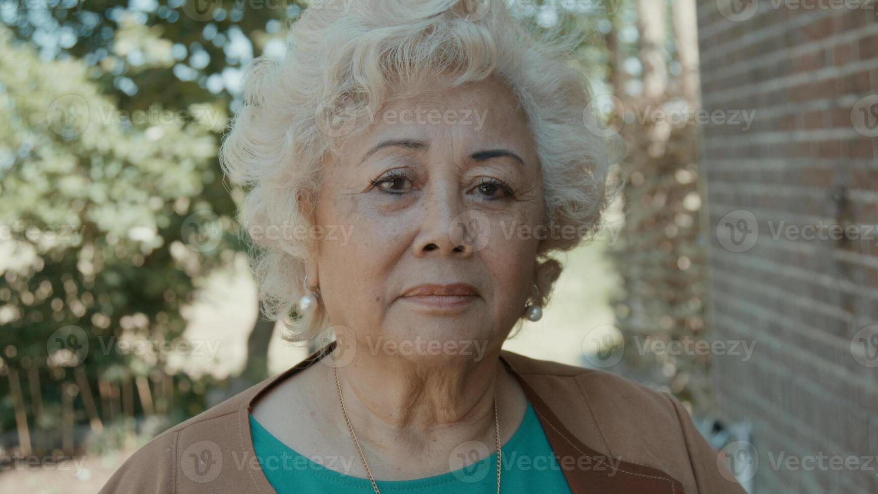 Woman standing in yard looking serious into camera lens photo