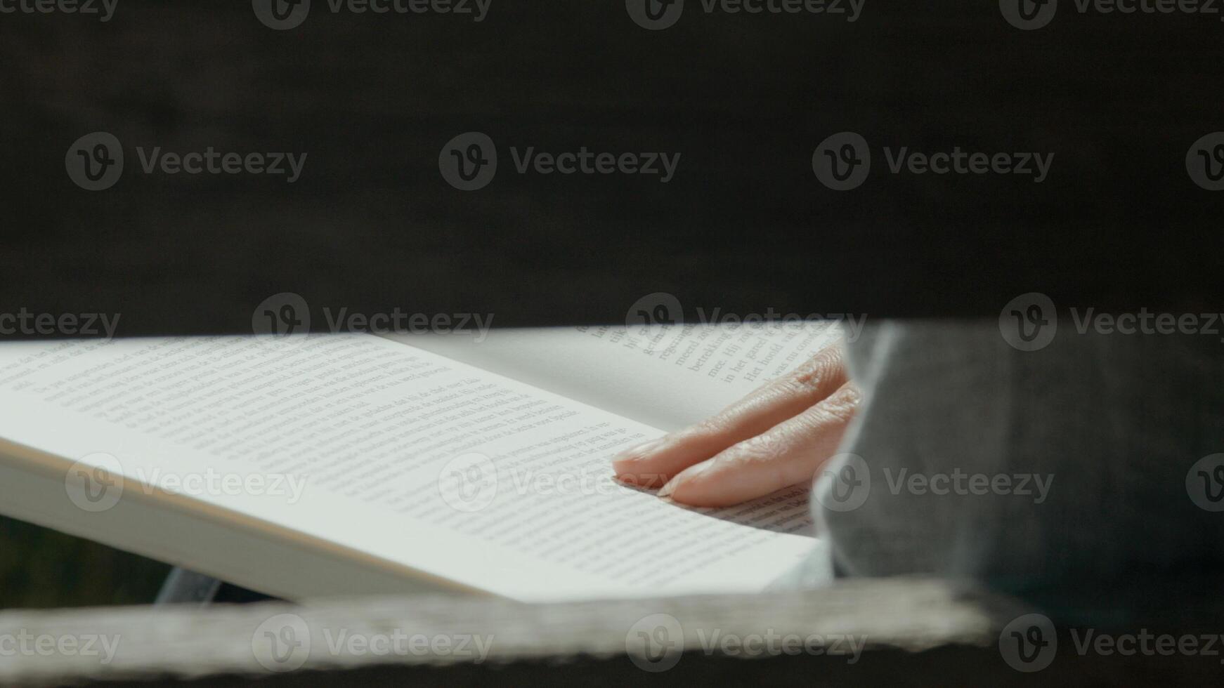 Woman sitting on wooden bench in the country reading a book photo