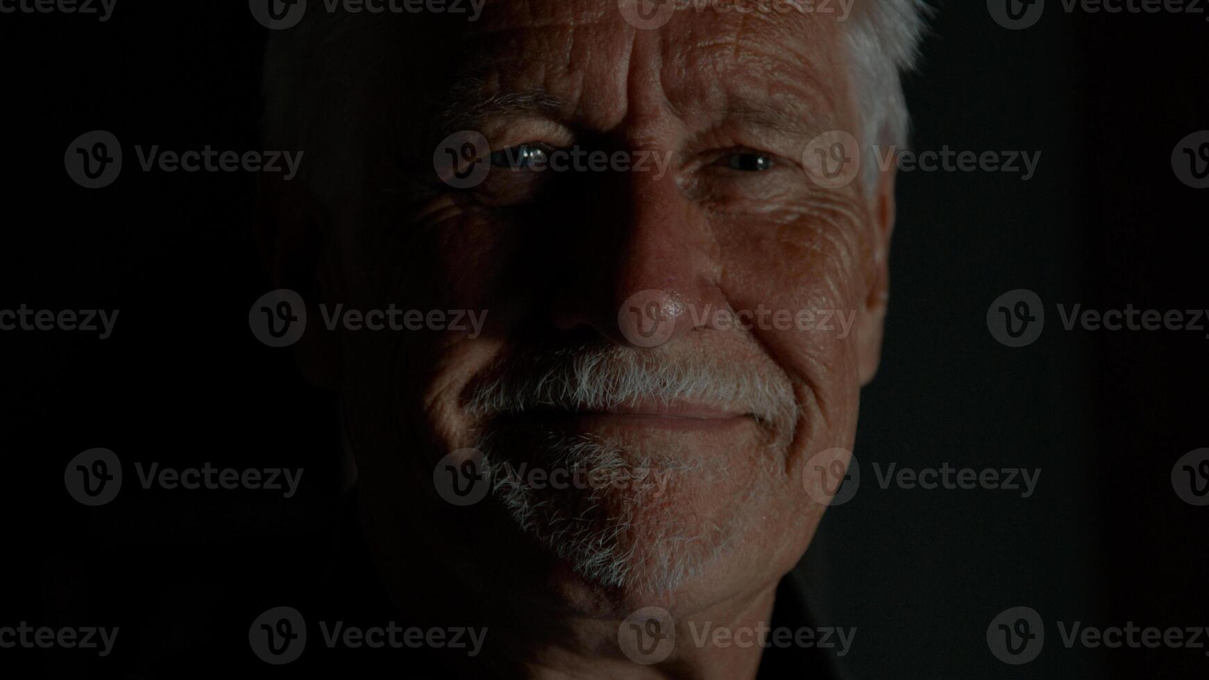 Man looks angry and smiles again whilst looking into camera lens photo