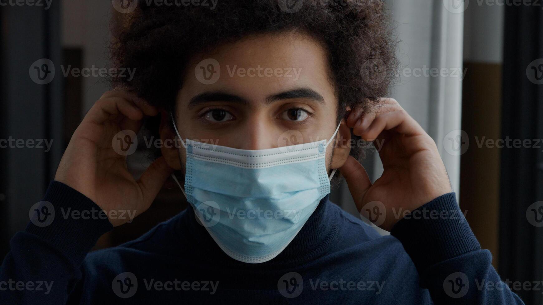 Close up of young Middle Eastern man adjusting face mask photo