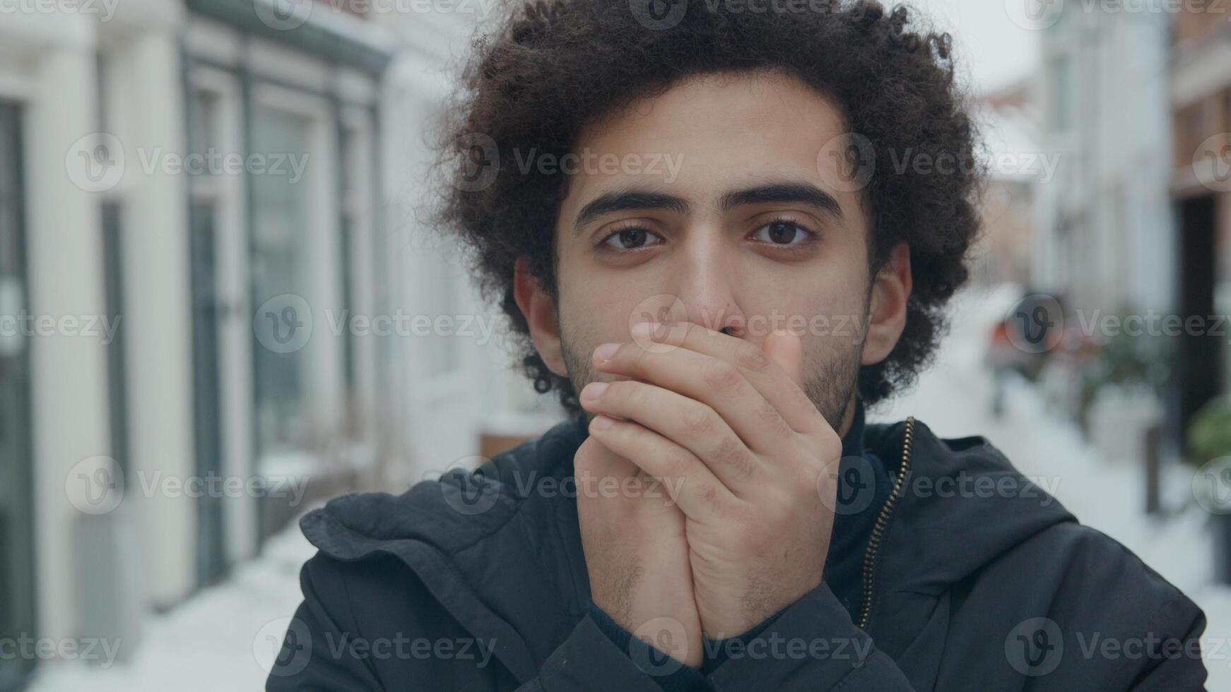 Cerca del hombre de Oriente Medio soplando aire caliente en las manos foto