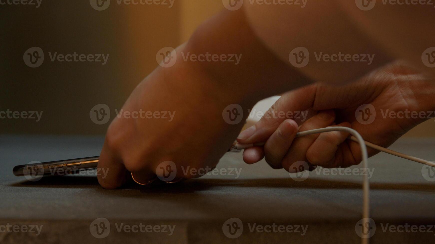 Close up of mobile phone, hands of young woman plugging cable photo