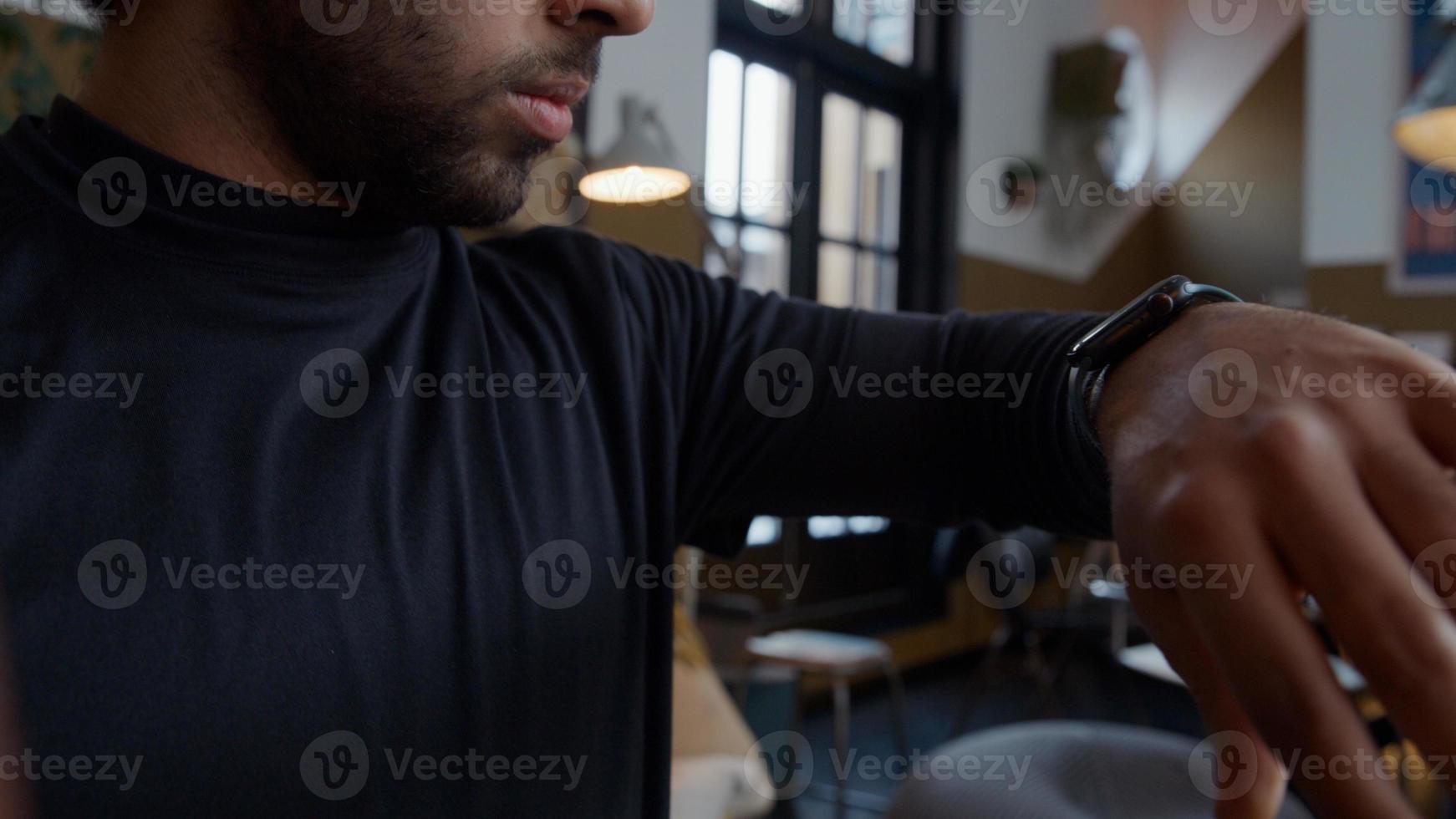 Young Middle Eastern man looks at smart watch, swipes on screen photo