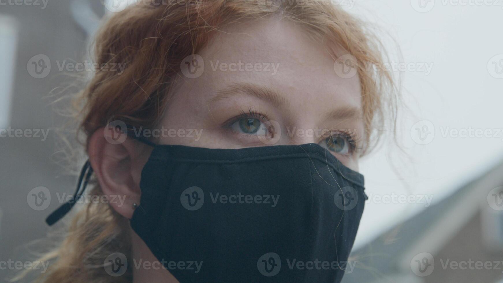 Cerca de la joven mujer blanca de pie afuera, vistiendo mascarilla foto