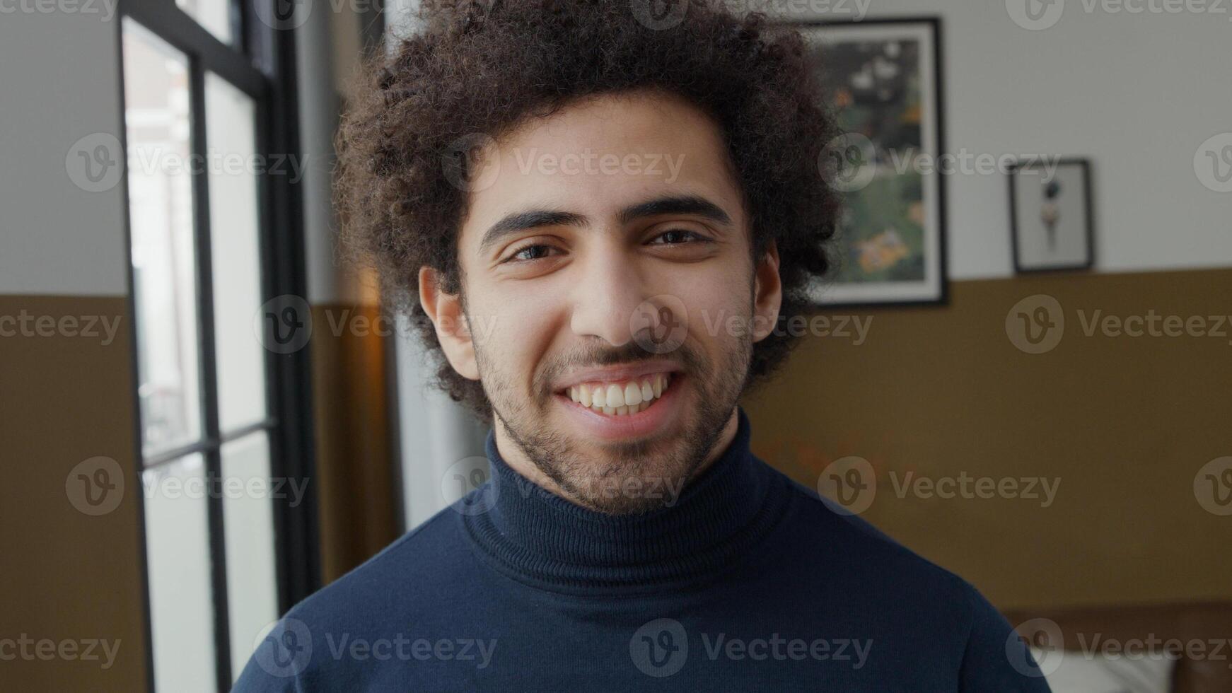 Close up of young Middle Eastern man looking into camera, laughing photo