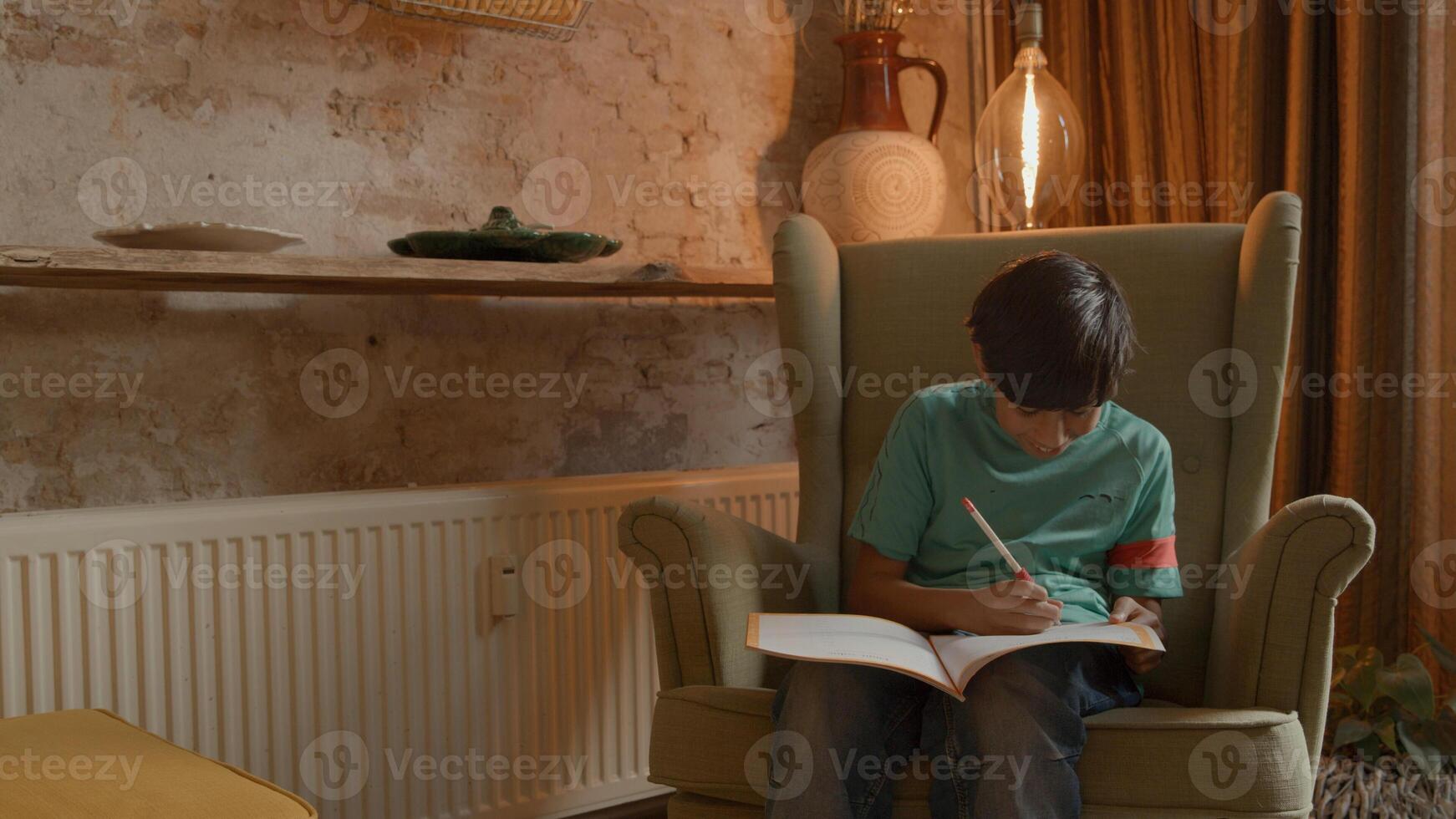 niño, en, sillón, escritura, en, libro de ejercicios foto