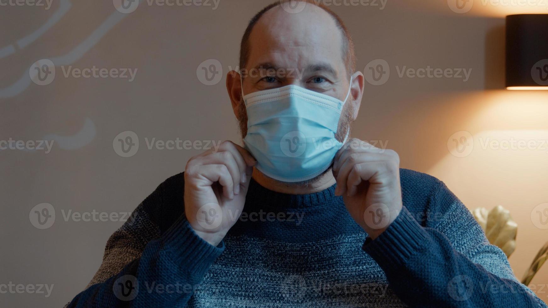Man putting on face mask looking into camera lens photo