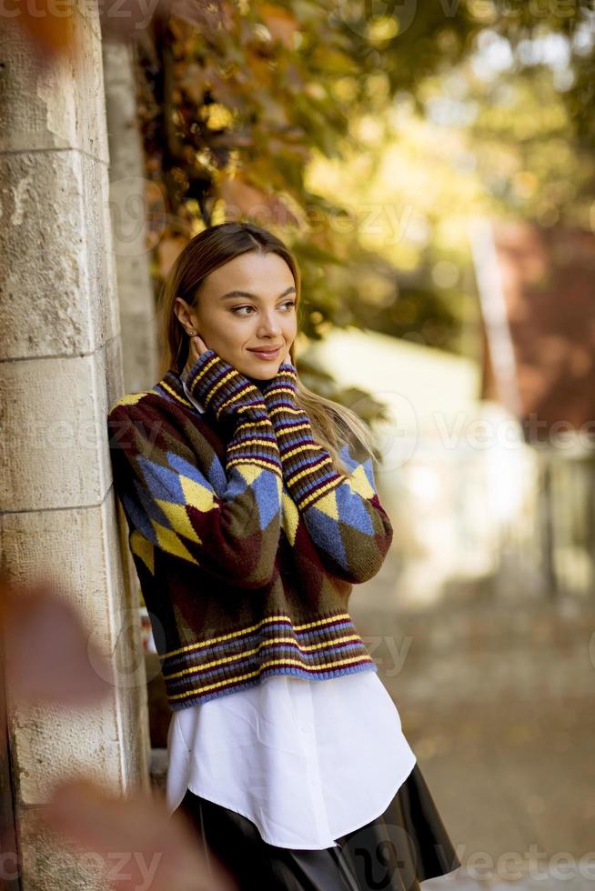 Mujer joven de pie afuera en el soleado día de otoño foto