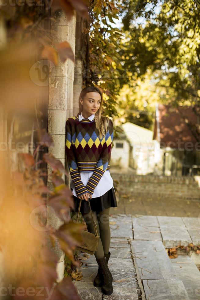 Mujer joven de pie afuera en el soleado día de otoño foto