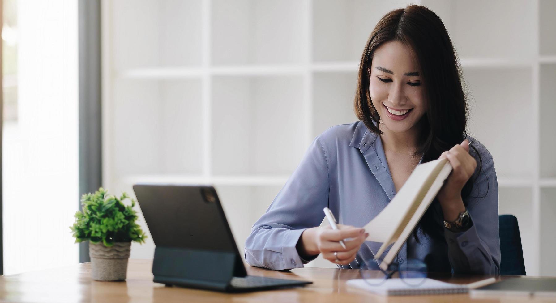 Business asian woman hand taking notes with various items placed photo