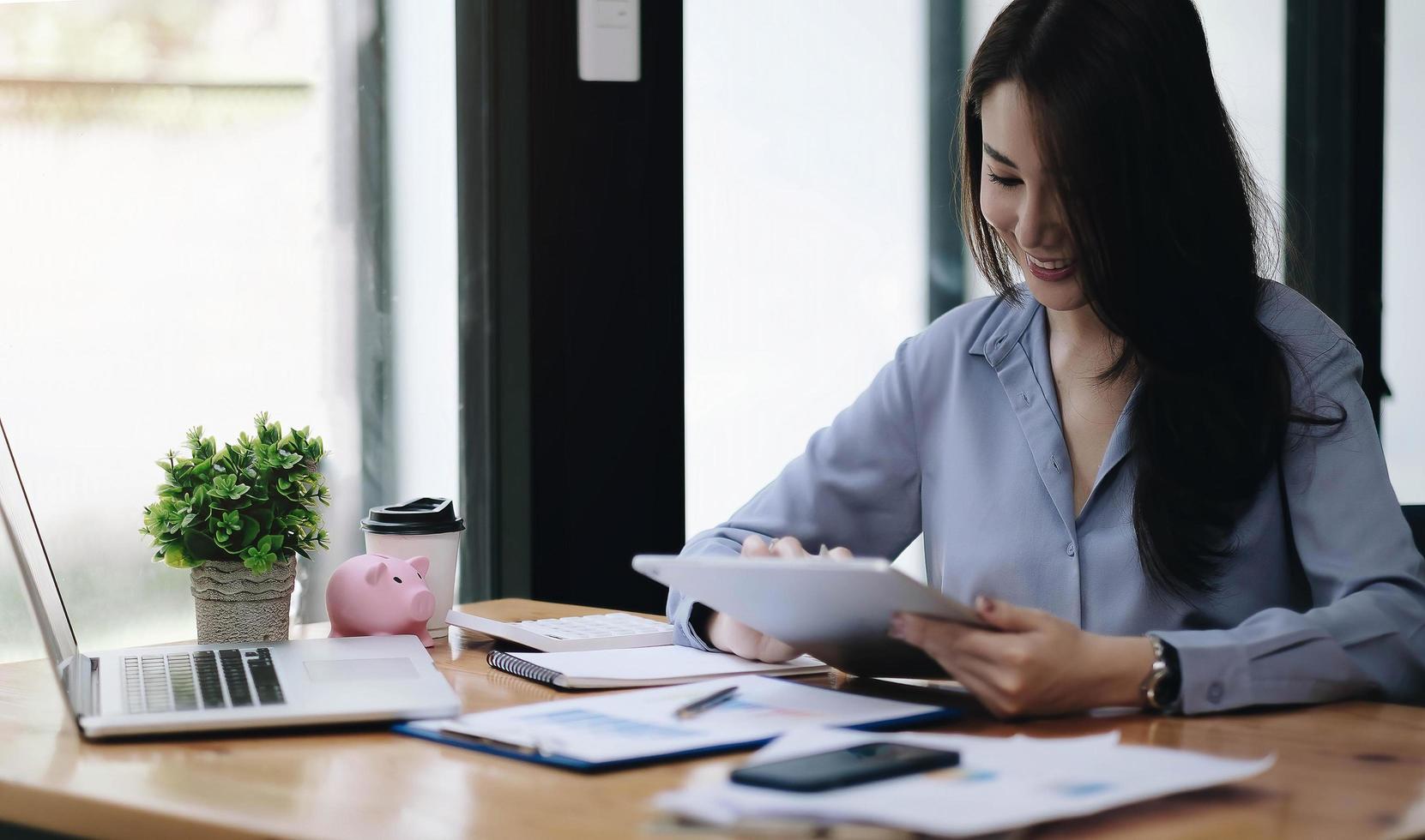 Business asian woman using laptop for do math finance on wooden photo