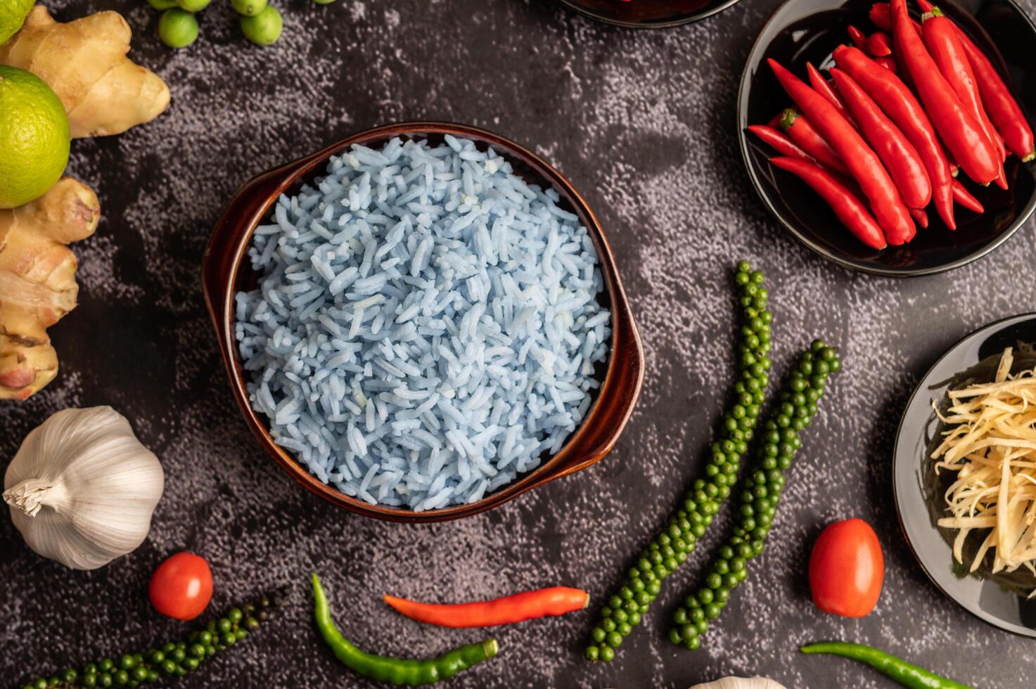 arroz de flor de guisante de mariposa en una taza marrón con especias sobre cemento negro. foto