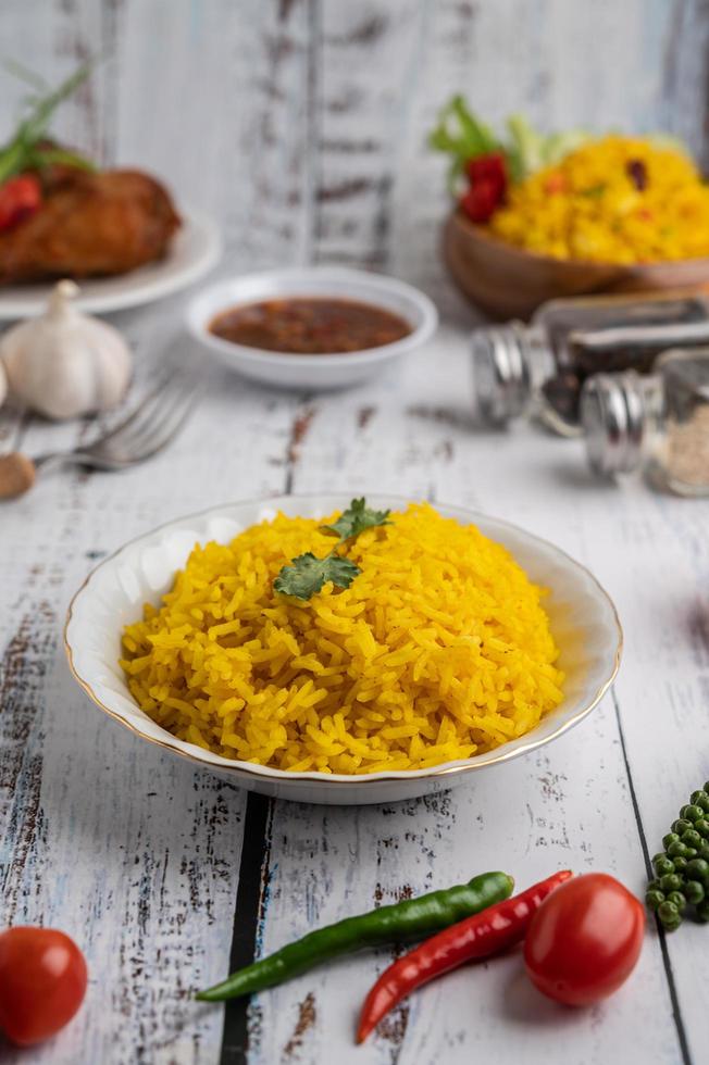 Turmeric rice in a white plate with spices on a white wooden floor photo