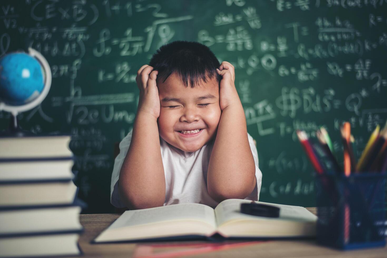 Niño preocupado en el aula con las manos en la cabeza. foto