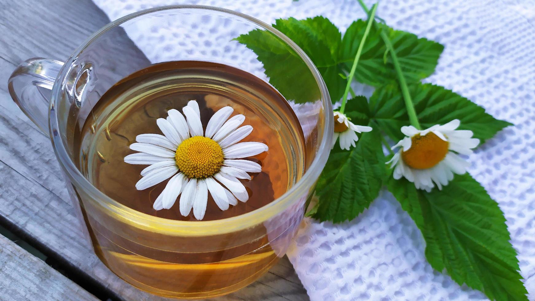 Chamomile tea in a glass cup close-up on a wooden background photo