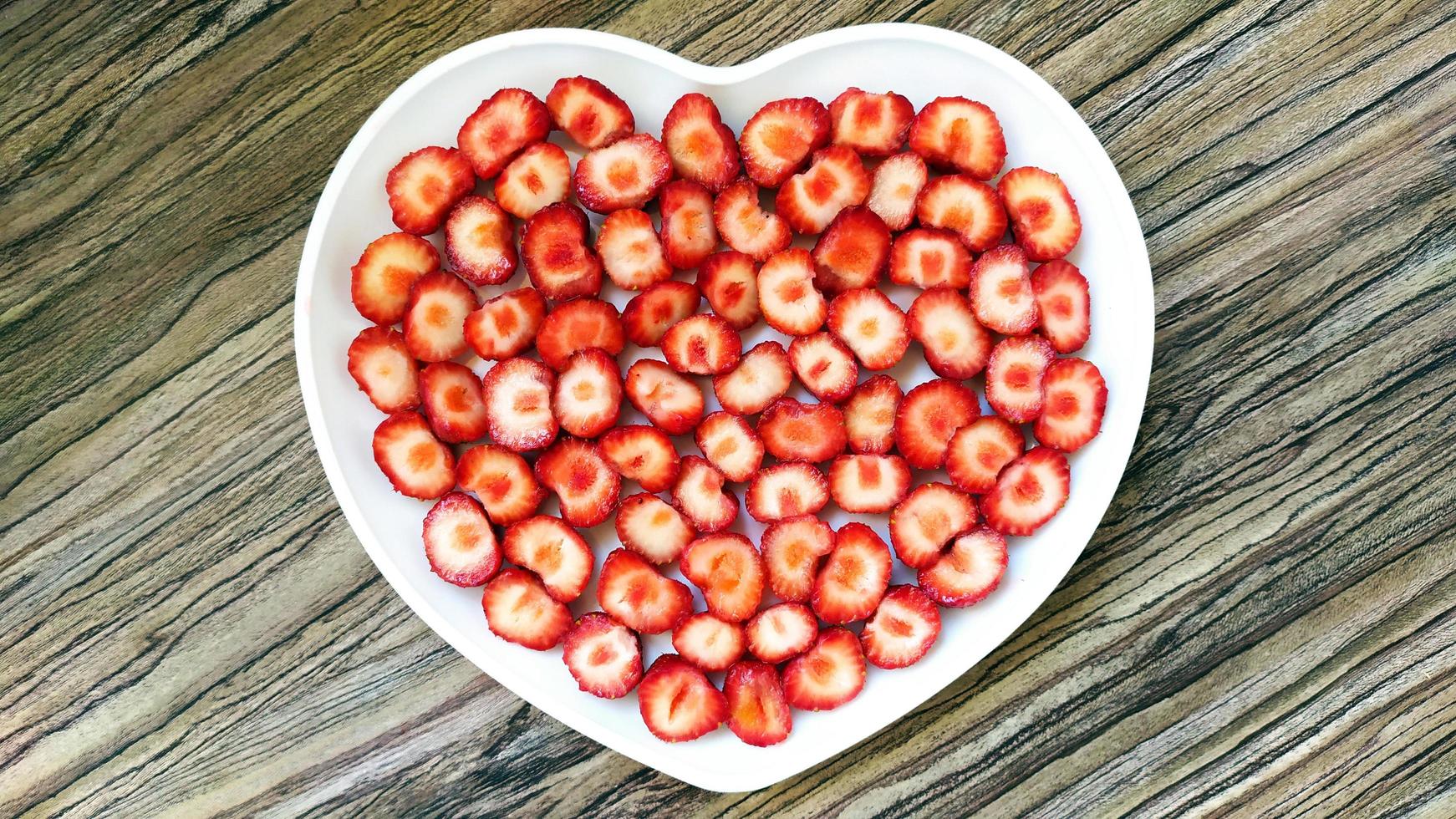 The sliced strawberries are in a heart-shaped plate photo