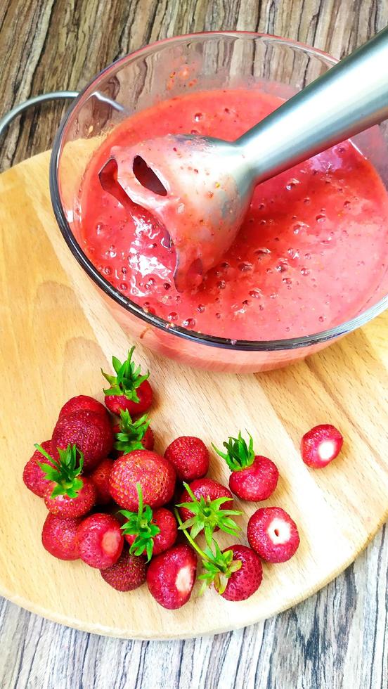 Preparing ripe strawberry fruit puree with an electric blender photo