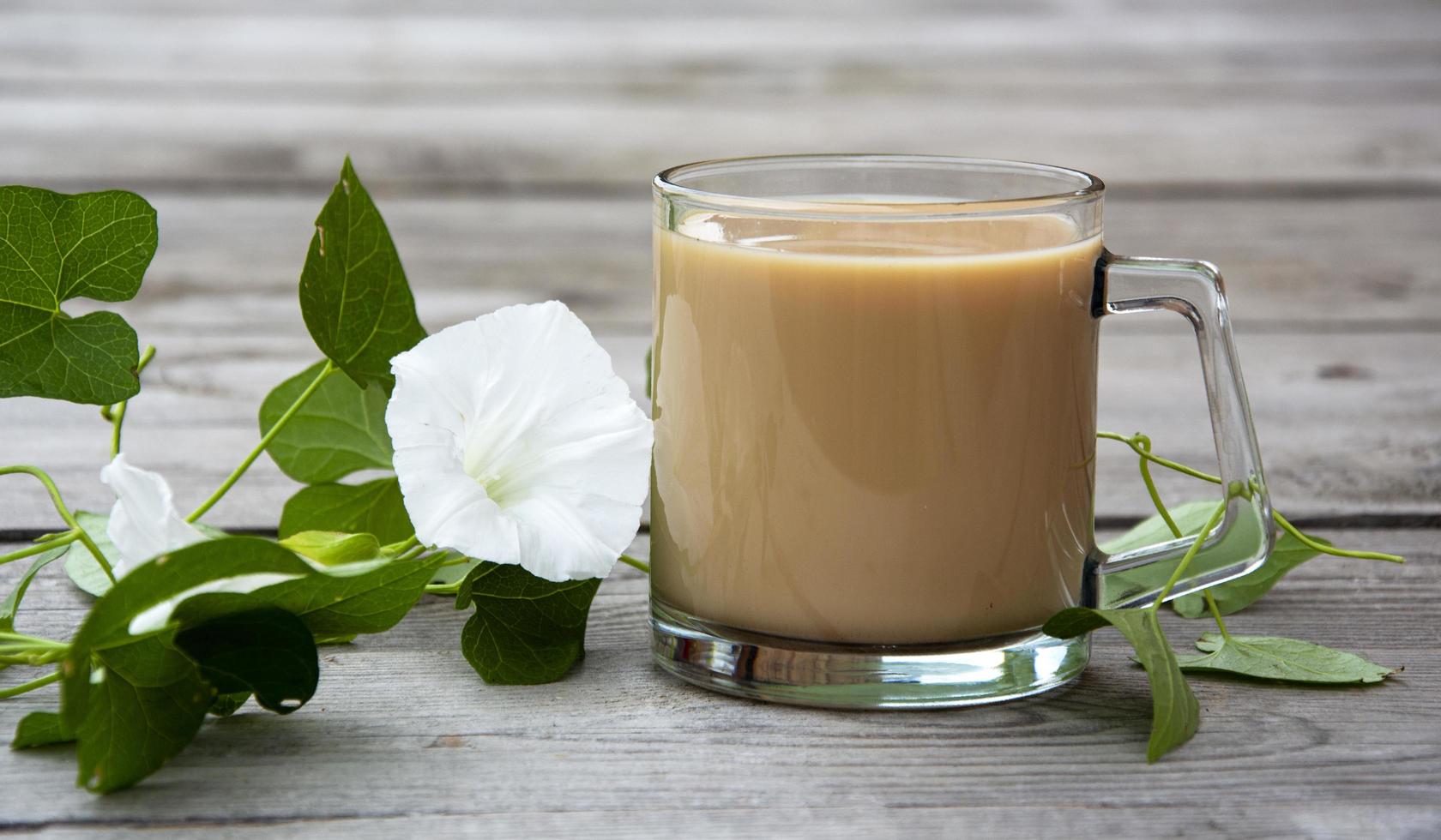 Taza con cacao y loach con flores blancas sobre un fondo de madera foto