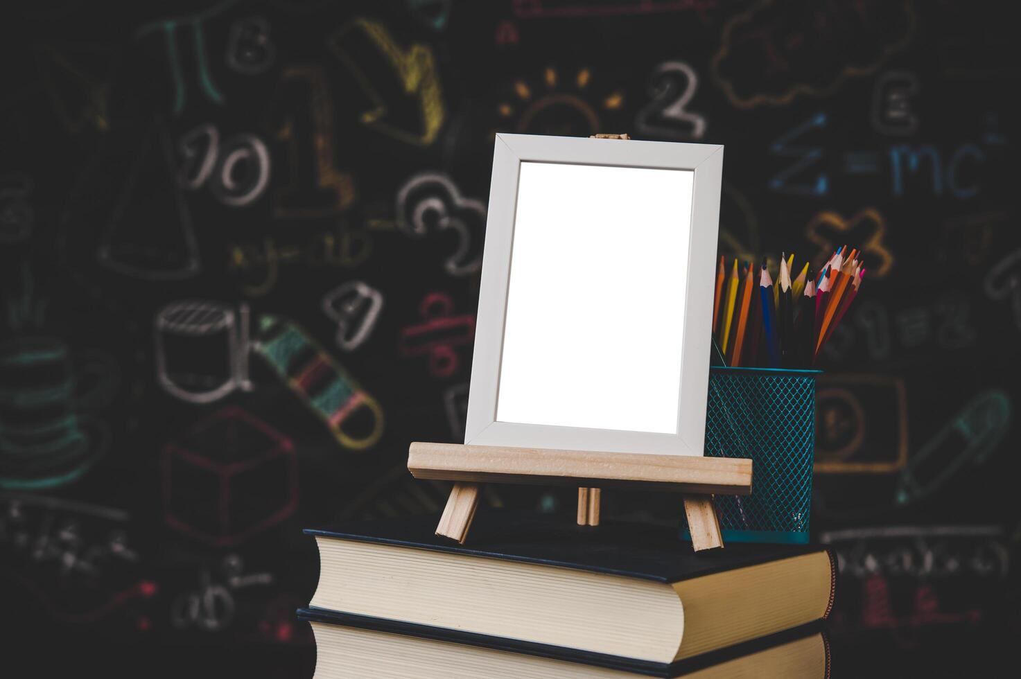 white photo frame on the stand and colored pencils on the books