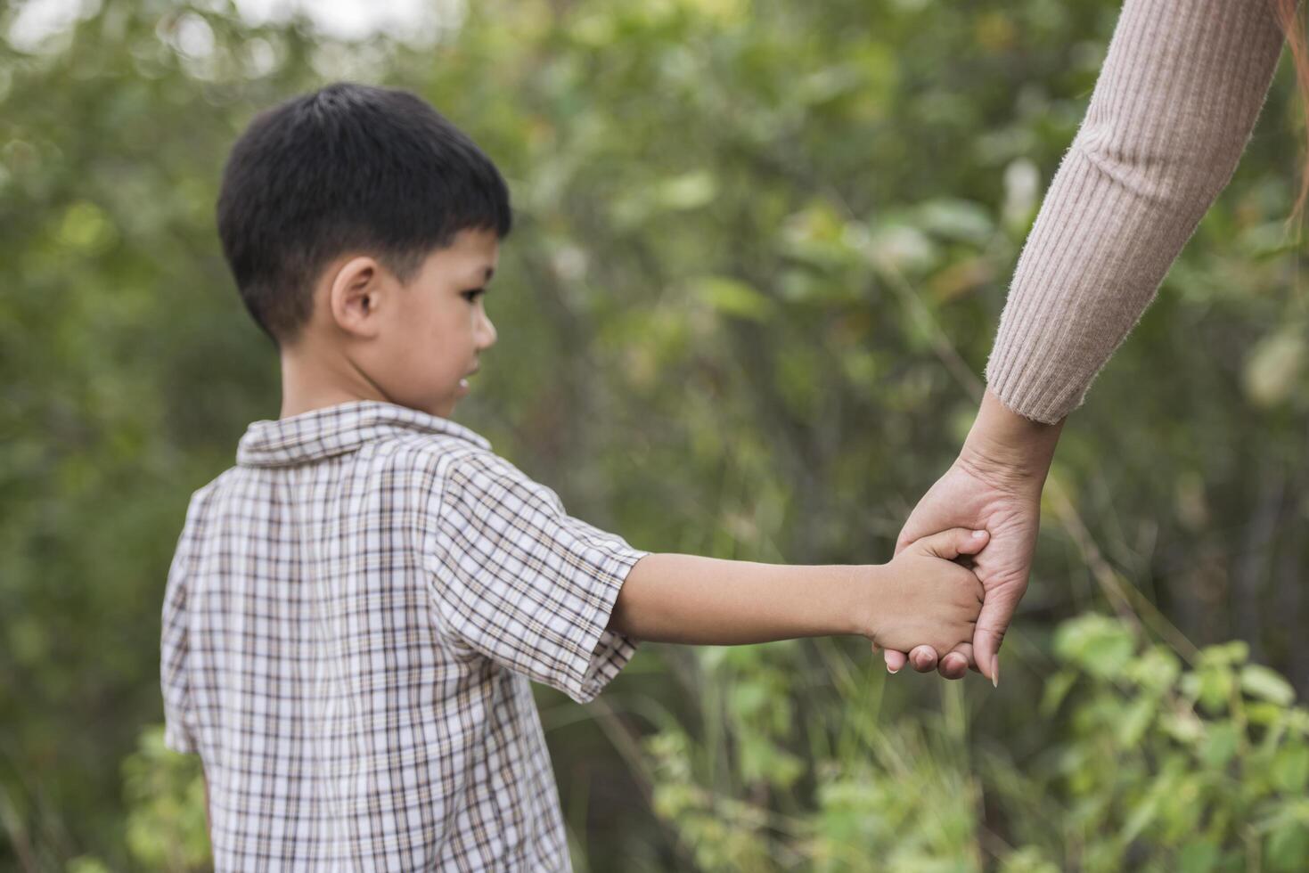 Close up of happy mum and son holding hand in a park. Family concept. photo