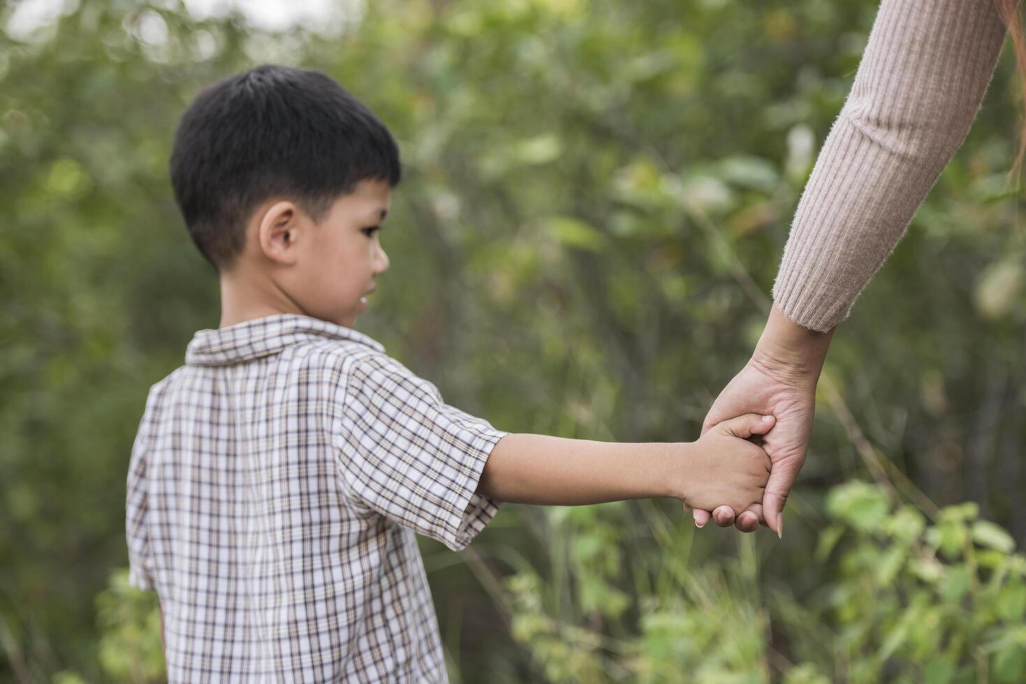 Cerca de feliz madre e hijo cogidos de la mano en un parque. concepto de familia. foto