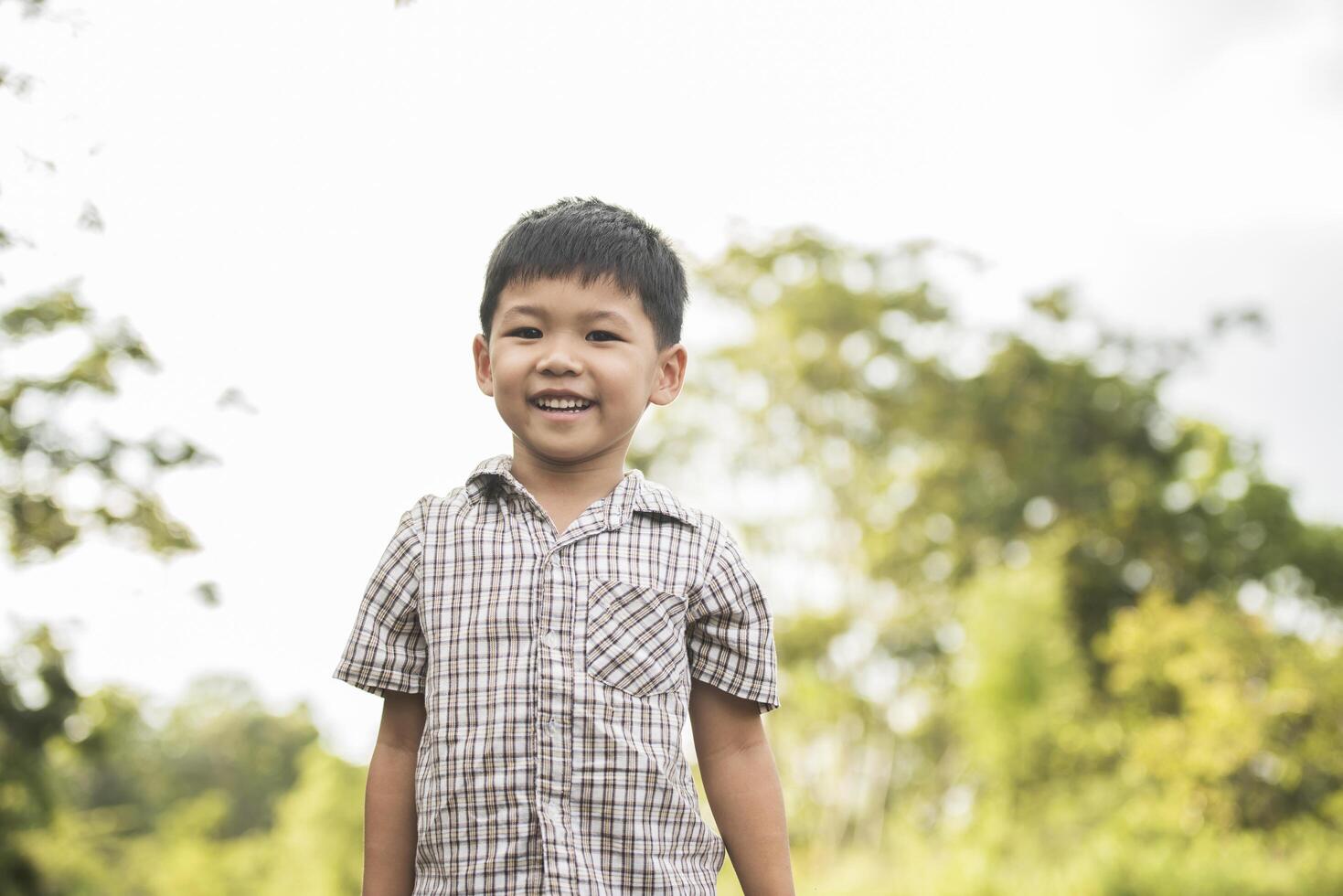 retrato de niño de pie en el parque natural sonriendo a la cámara. foto