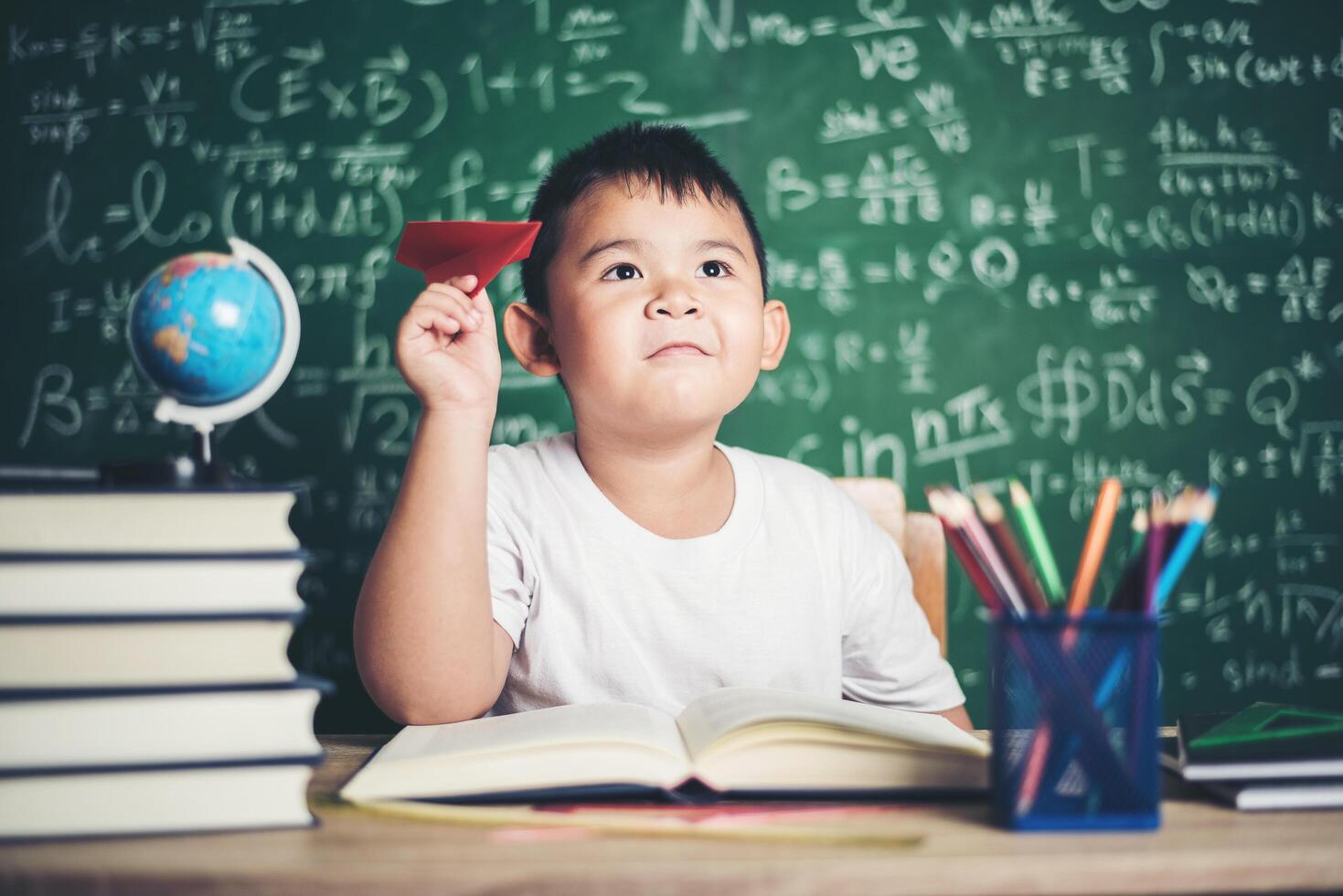 retrato, de, niño, con, un, avión de papel, en, aula foto