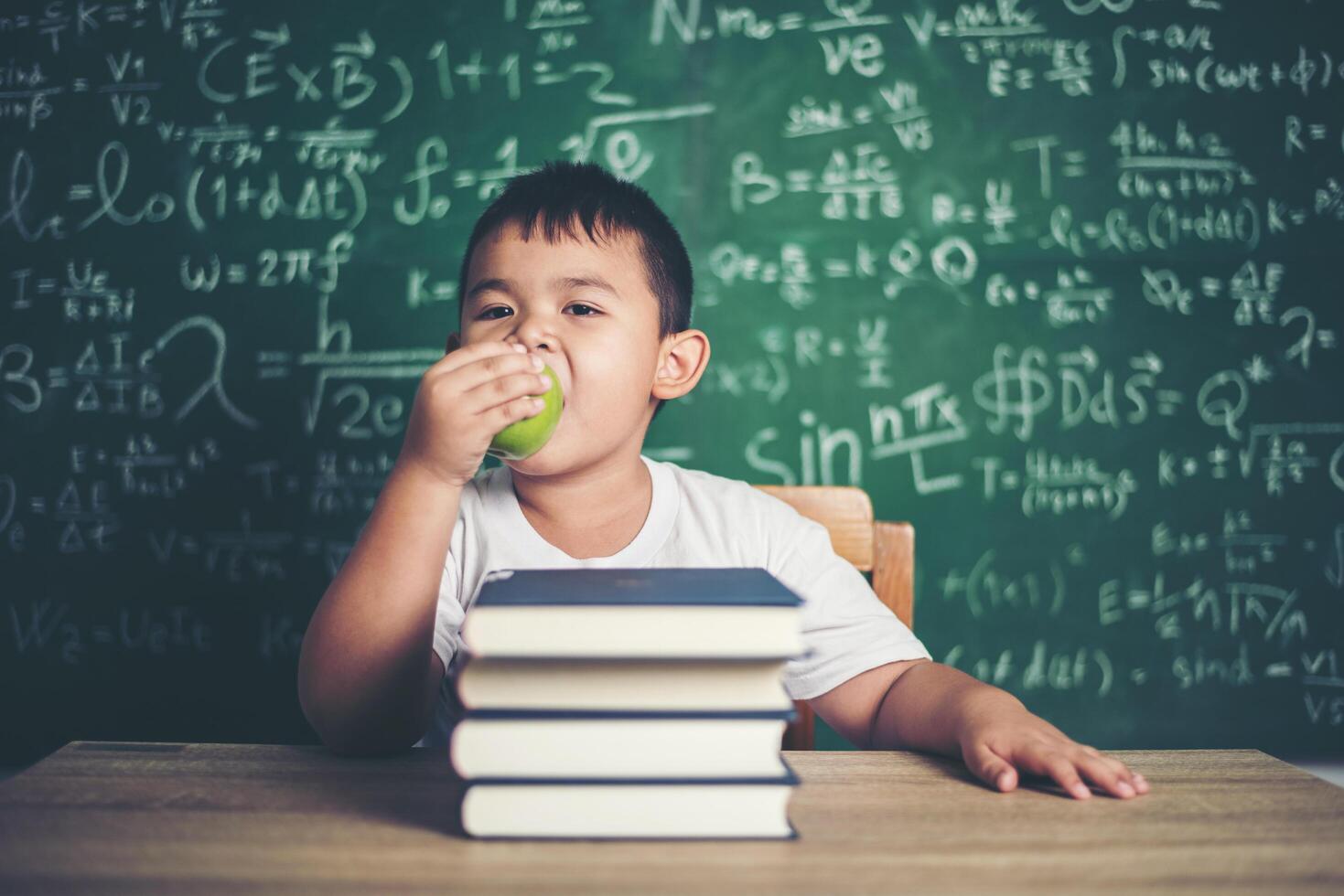 girl holding a apple in the classroom photo