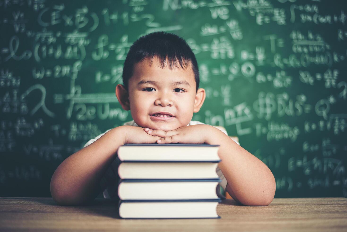 niño con libros sentado en el aula foto