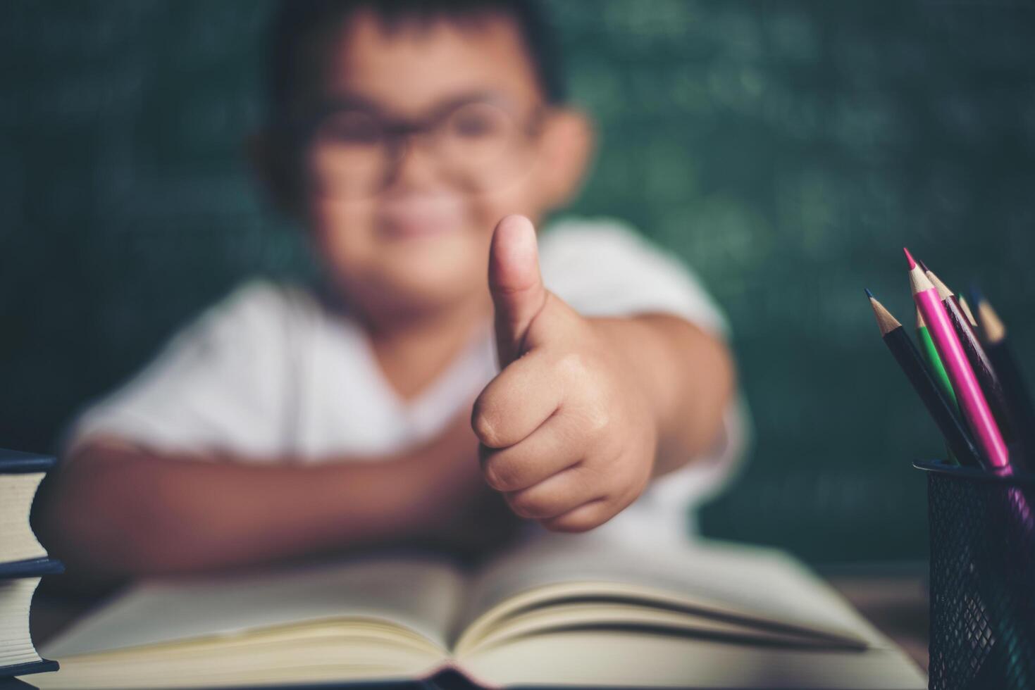 Portrait of a boy with hands thumbs up in the classroom. photo