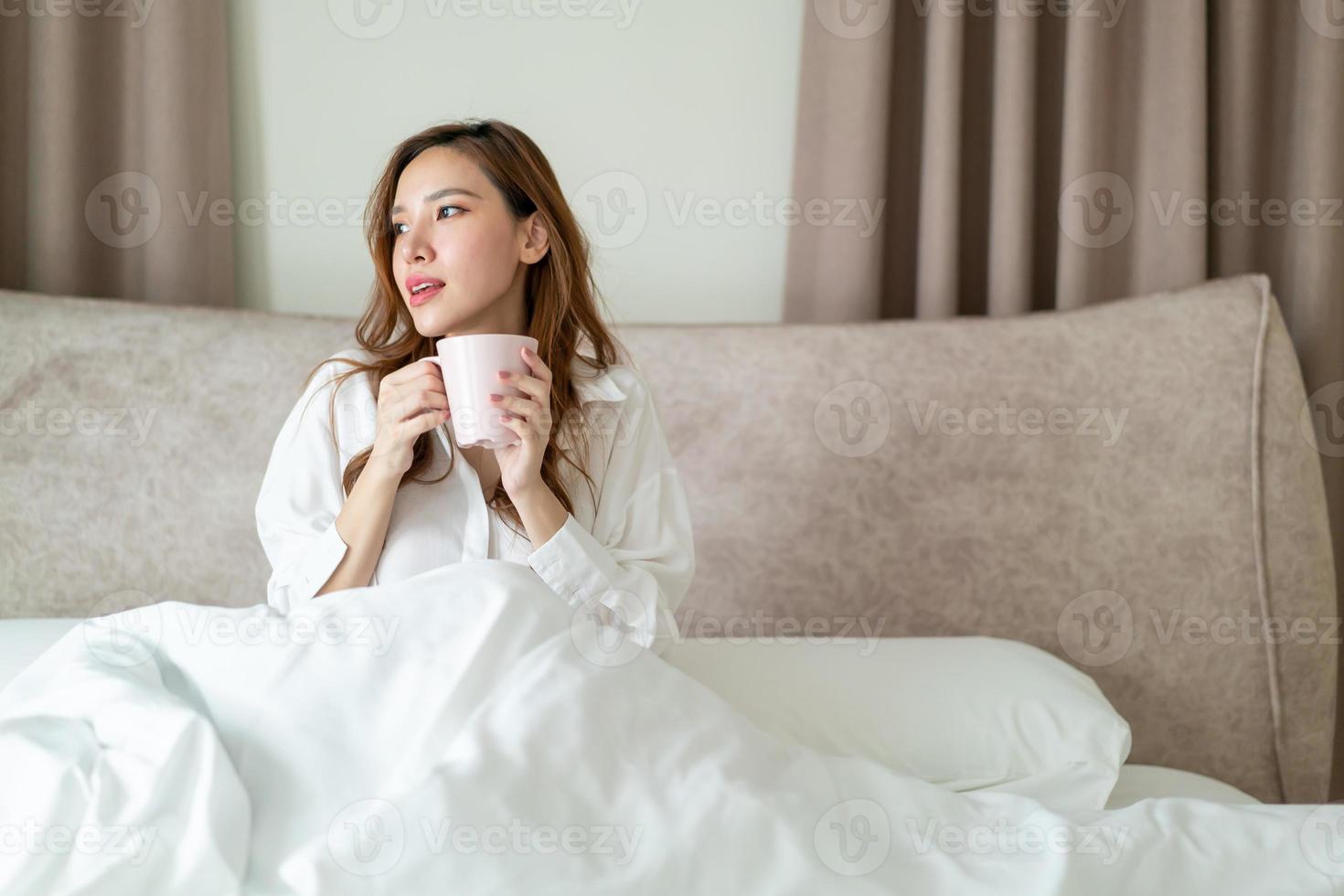 retrato, mujer hermosa, despertar, y, tenencia, taza de café, o, taza, en cama foto