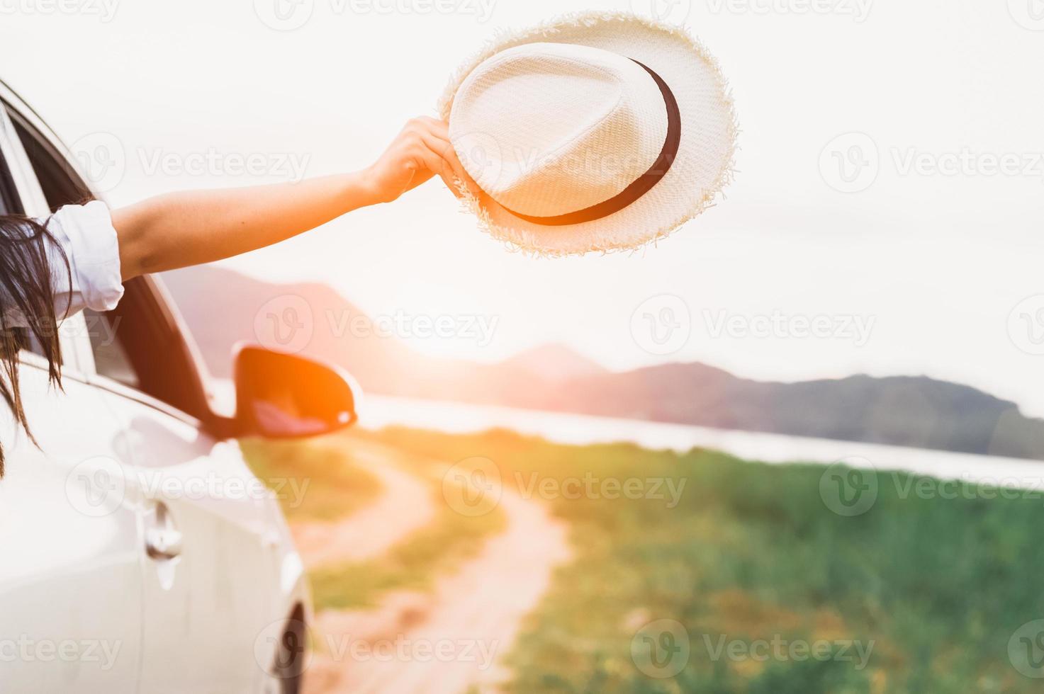 Happy woman hand holding hat outside open window car photo