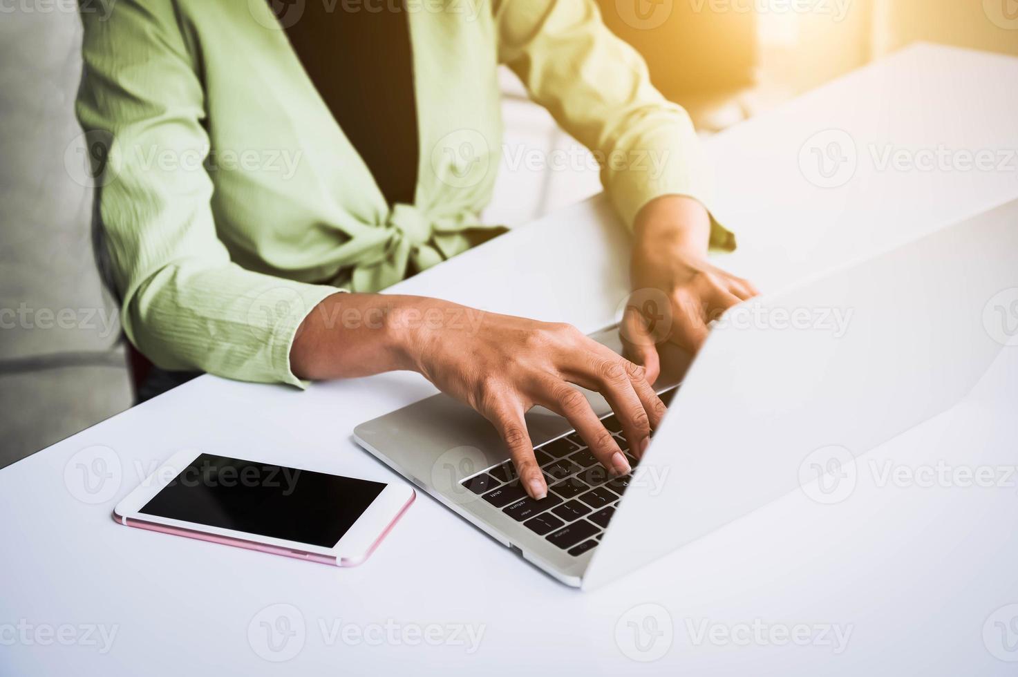 Primer plano de la mano de una mujer trabajando en la oficina en casa y escribiendo en el teclado foto