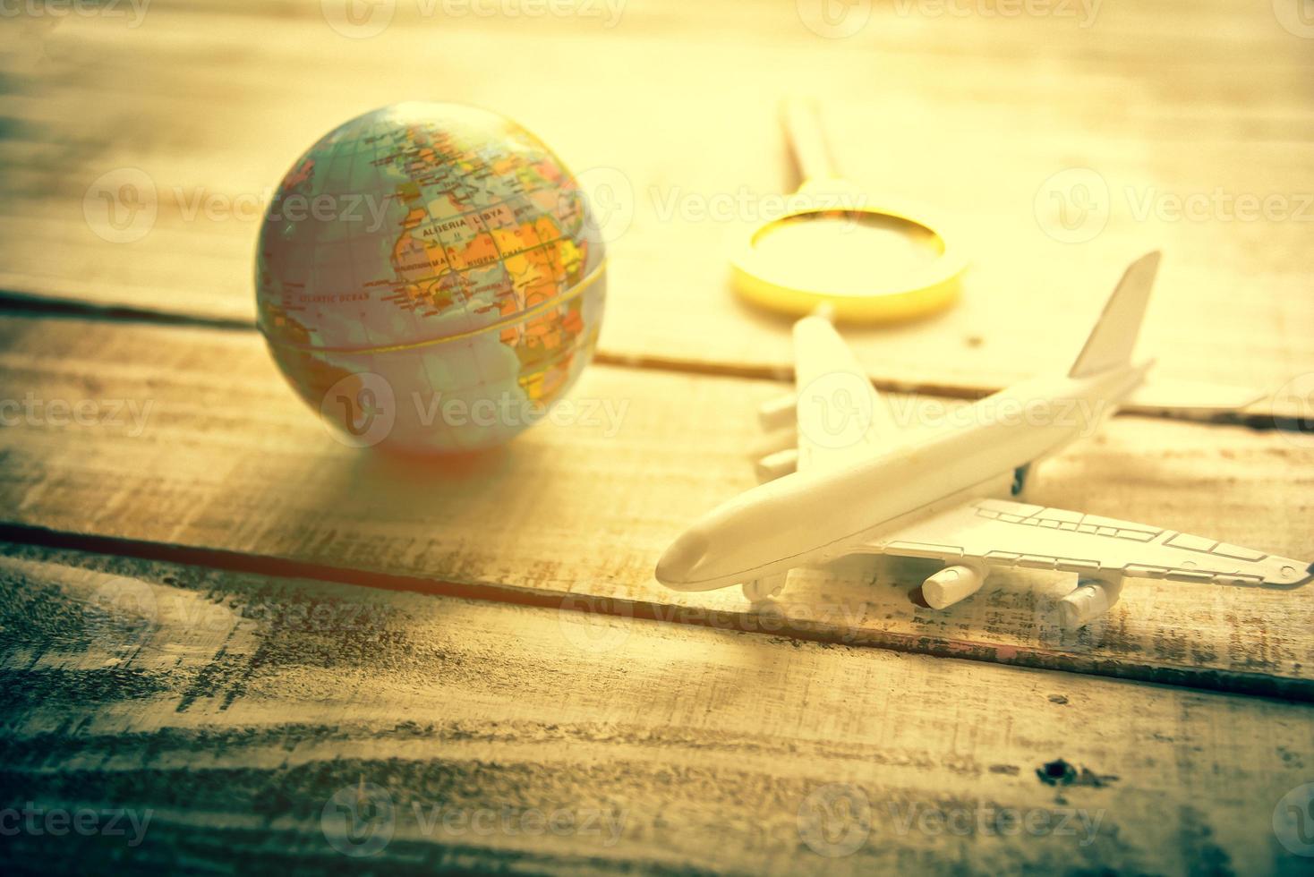 Small airplane and Globe and Magnify Glasses on wooden table photo