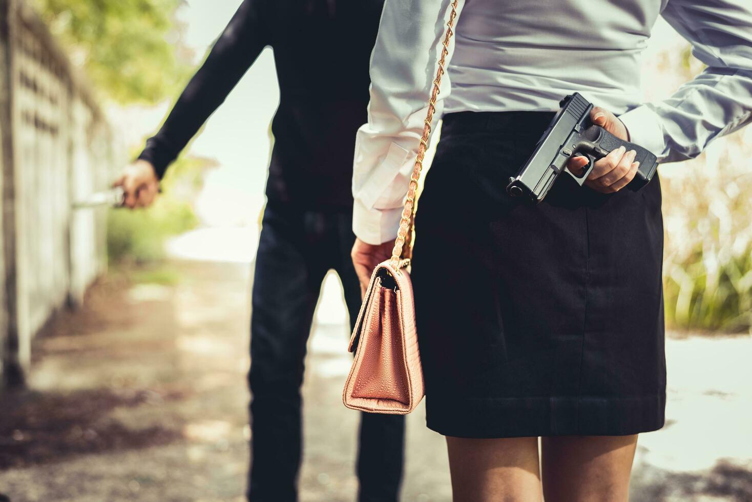 Cerró de mujer escondiendo la pistola de mano en la espalda para luchar contra el ladrón foto