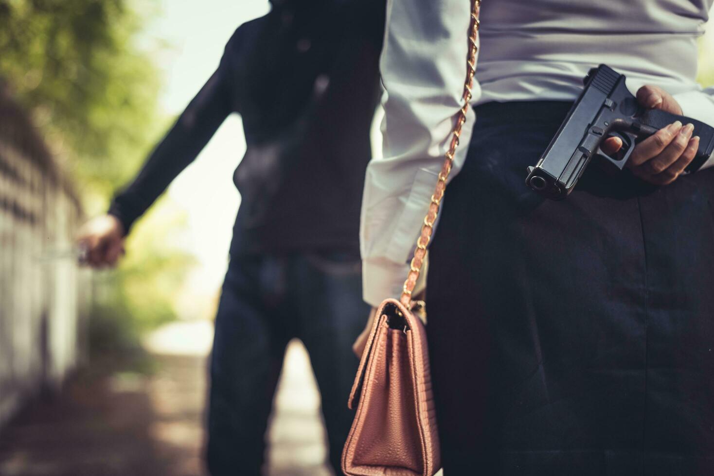 Cerró de mujer escondiendo la pistola de mano en la espalda para luchar contra el ladrón foto