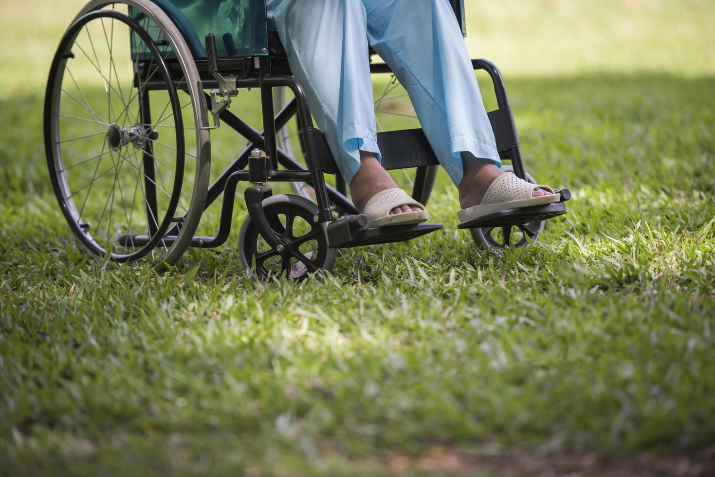 Cerrar solitaria anciana sentada en silla de ruedas en el jardín foto
