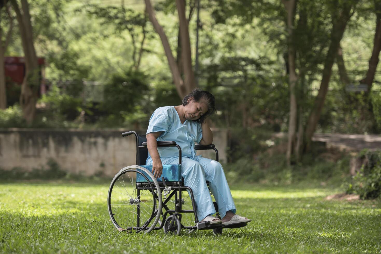 Anciana solitaria sentada sensación de tristeza en silla de ruedas en el jardín foto