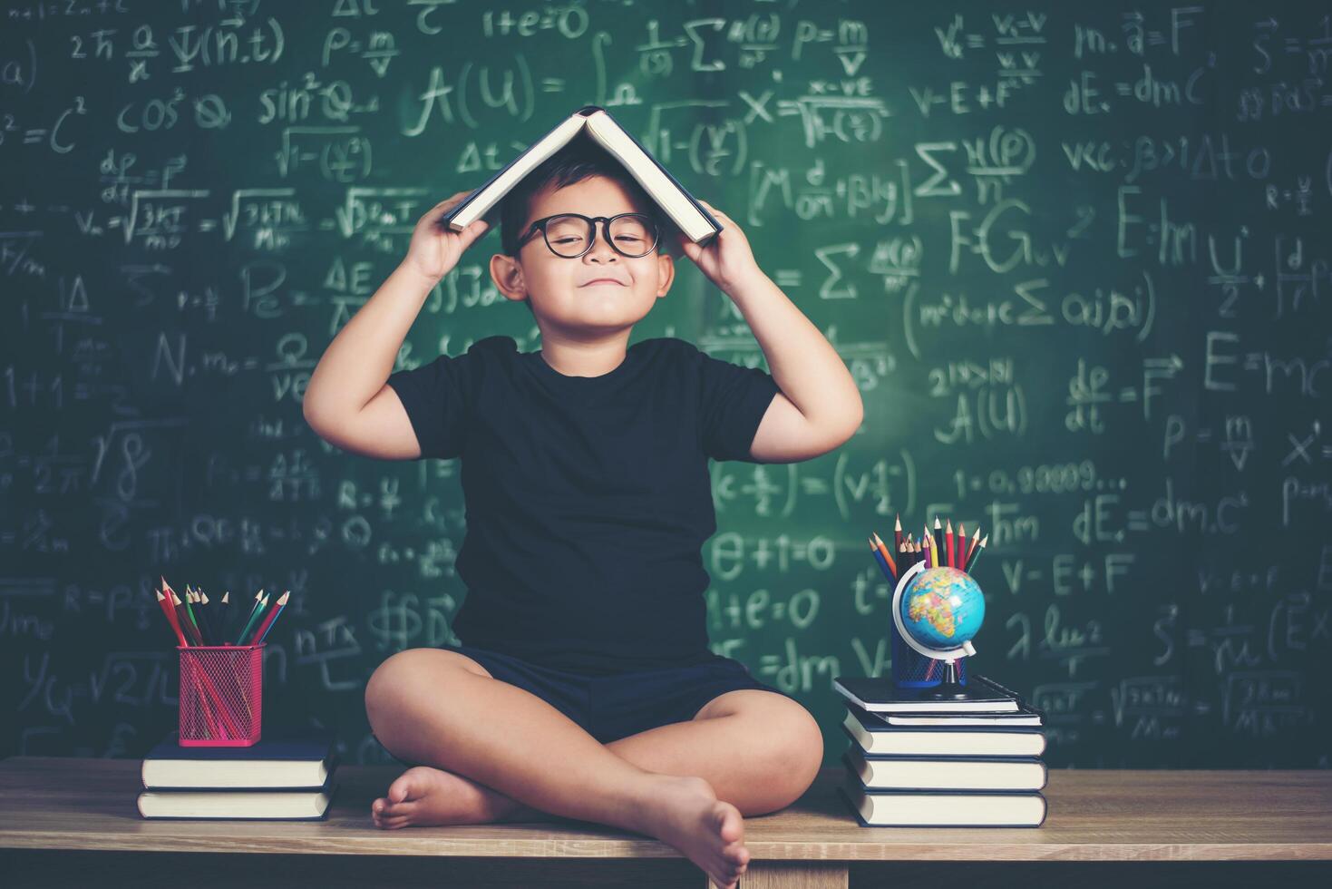 retrato, de, sonriente, colegial, sentado, en, el, mesa, con, libros foto